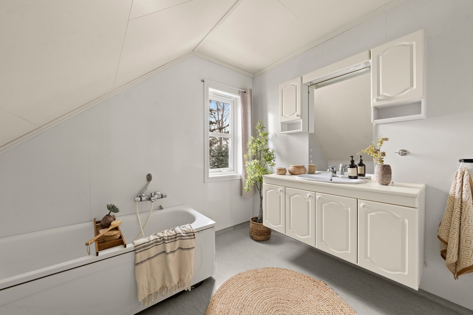 Baderommet i andre etasje er fra byggeåret. Rommet har baderomsplater på vegger, vinylbelegg på gulvet og himlingsplater i taket. Rommet er innredet med servant med underskap, toalett, panelovn og badekar. Galleribilde