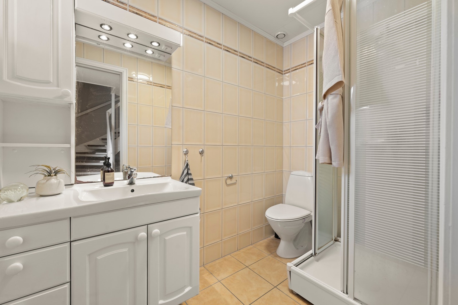 Badet er opprinnelig fra byggeåret og ble oppgradert i 2001. Det består av malt møblement med nedfelt servant, toalett og dusjkabinett. Varmekabler i gulv. Galleribilde