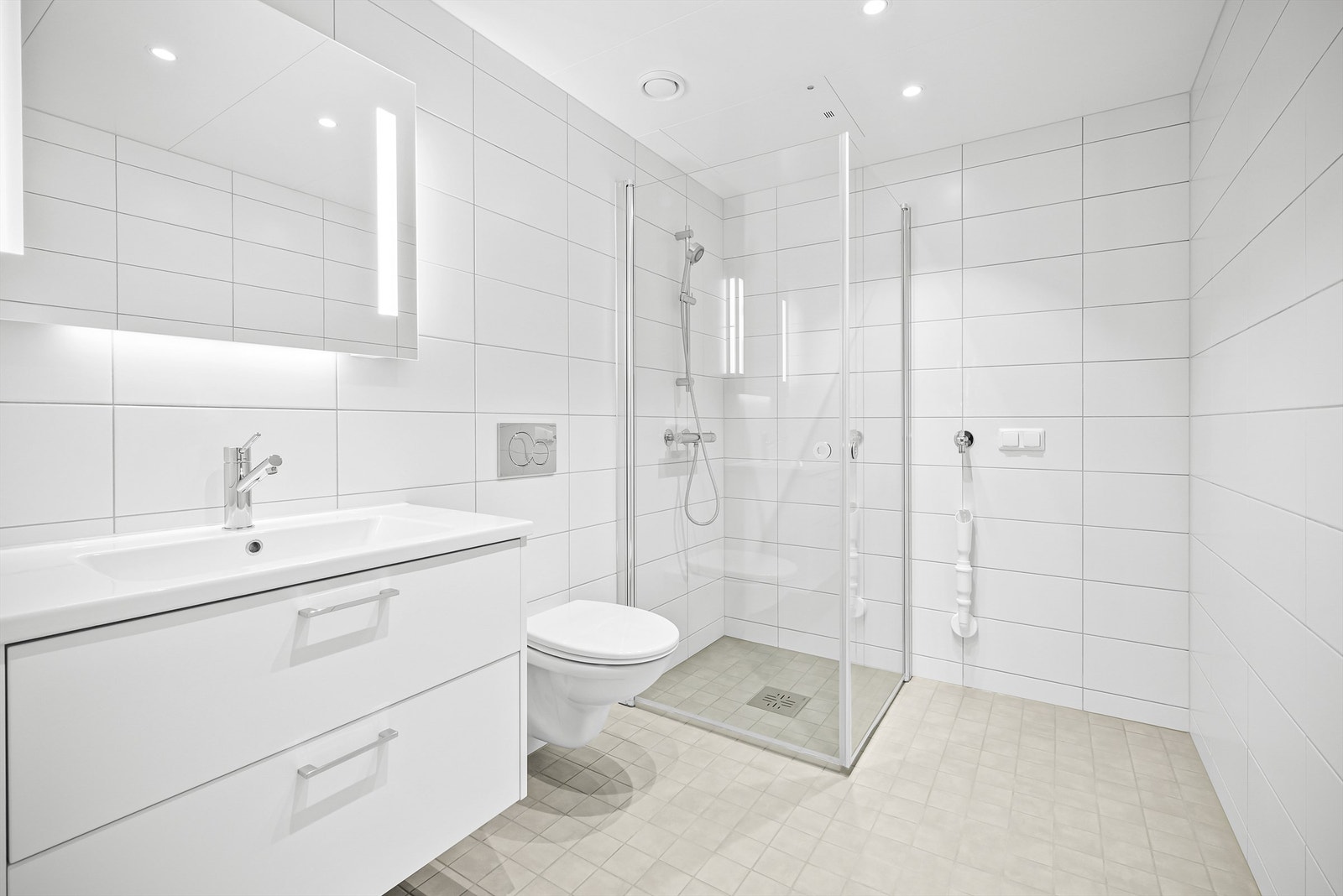 Lyst flislagt bad med dusjhjørne som har foldedører av glass Galleribilde