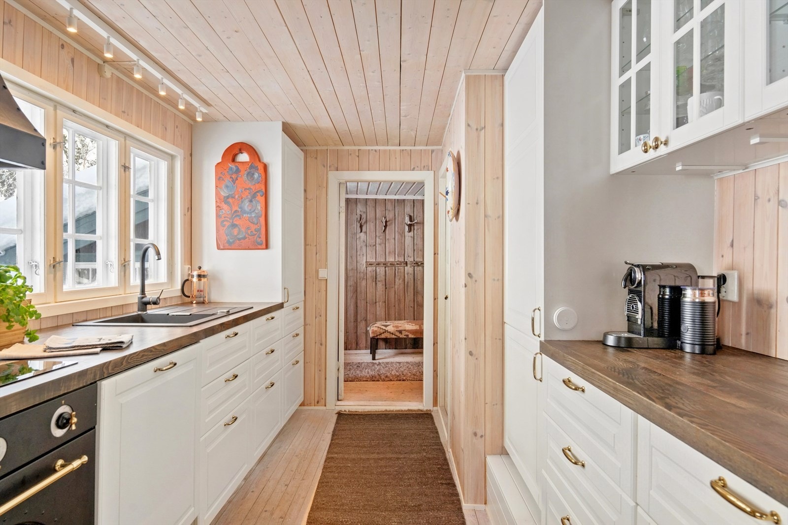 Kjøkkenet har en nyere IKEA-innredning med malte, profilerte fronter. Lang benkeplate gir god arbeidsplass, samt overskap med glassdører for praktisk oppbevaring. Galleribilde