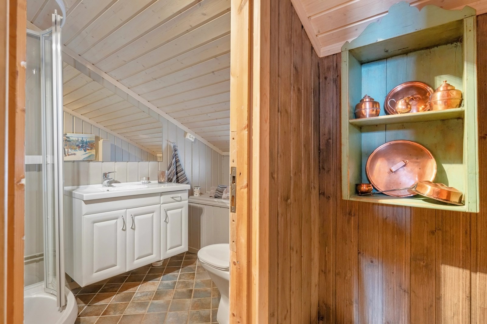 Rommet er innredet med en baderomsinnredning med helstøpt servantplate, gulvmontert vannklosett og et dusjkabinett. Galleribilde