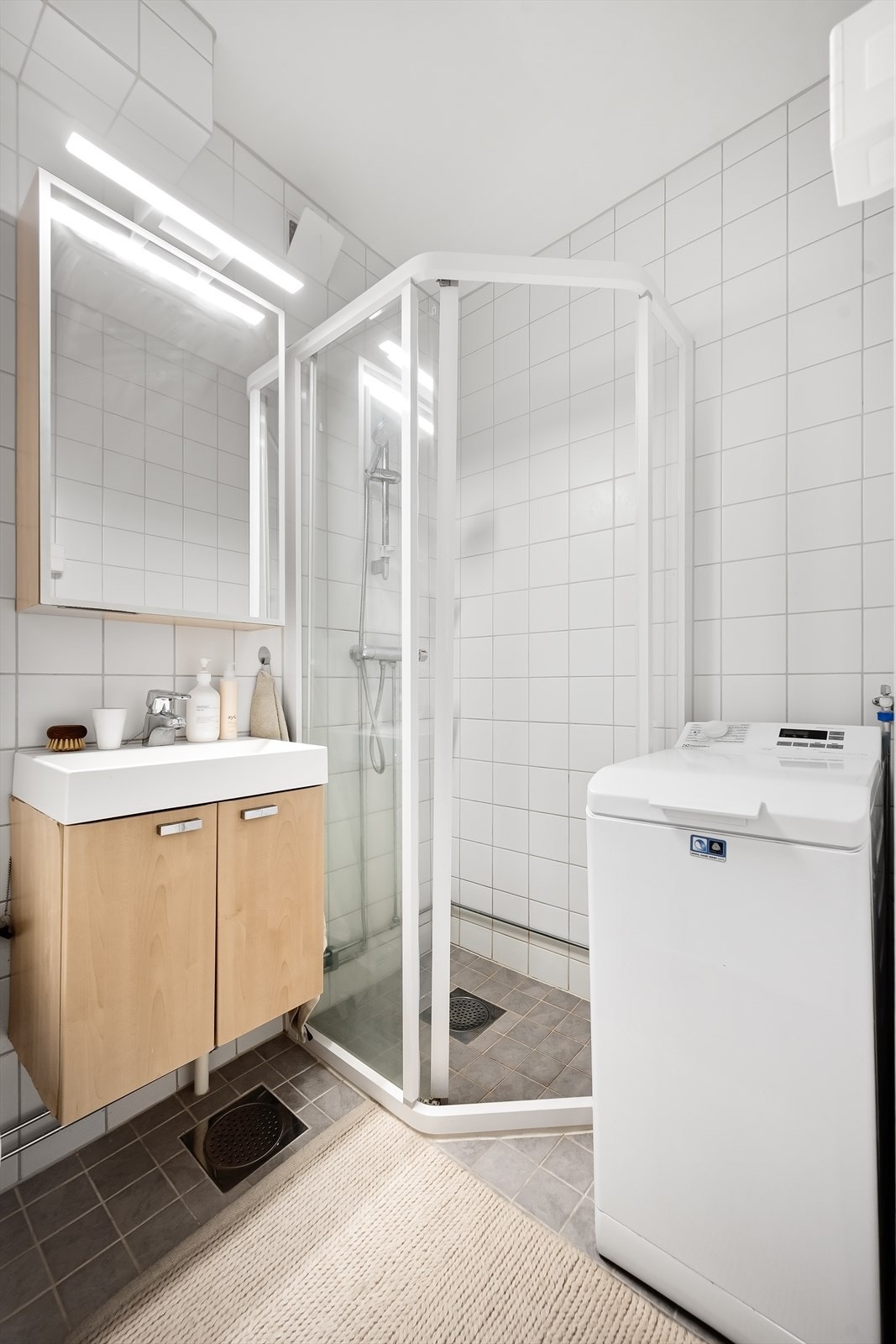 Rommet er innredet med dusjhjørne, servantmøbel og opplegg for vaskemaskin. Galleribilde