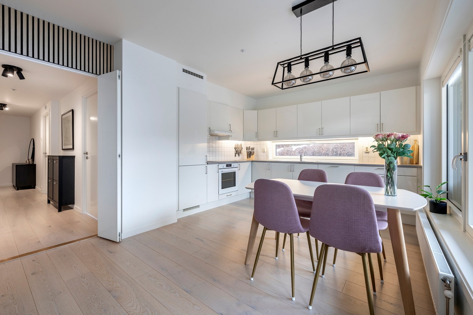 Kjøkkenet har en pen innredning med slette, hvite høyglans fronter og laminerte benkeplater med nedfelt oppvaskkum. Galleribilde