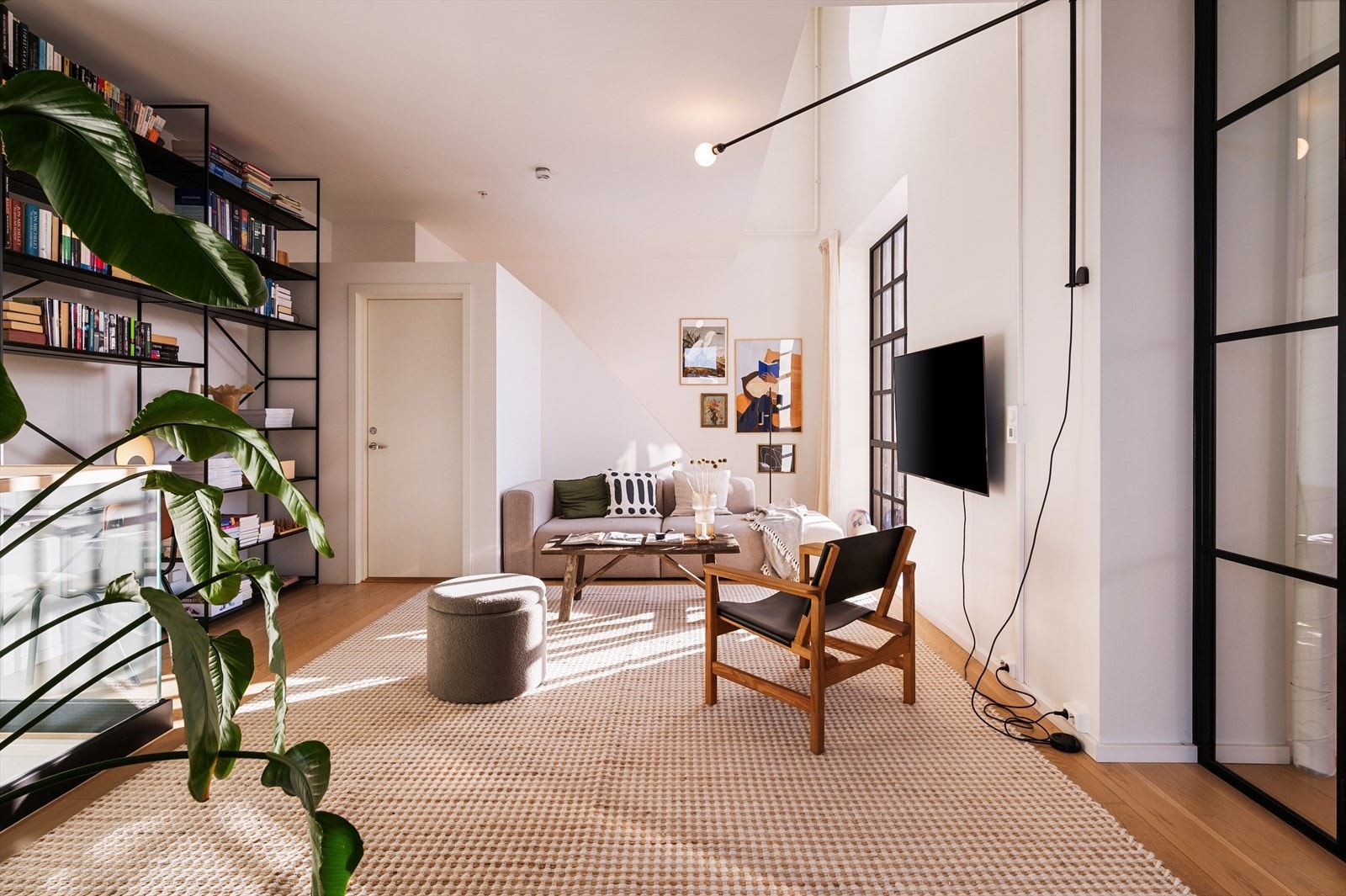 En del av stuen er avdelt og innredet som et romslig soverom, elegant skjermet med sorte glassdører. Galleribilde