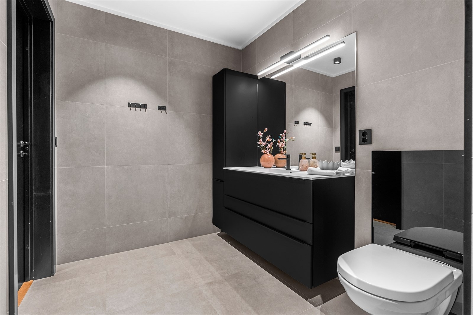 Badet er utstyrt med gulvvarme, dusjnisje, servantskap med oppbevaringsplass og veggmontert speil, samt veggmontert toalett. Galleribilde