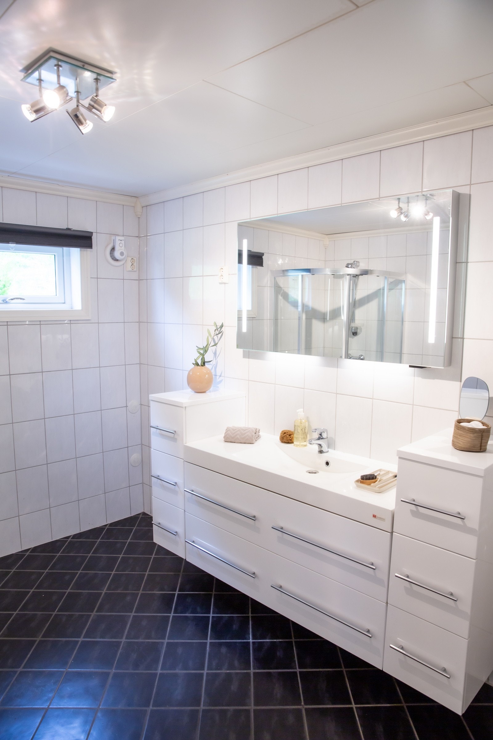 Begge badene har moderne og tidløse fliser med mørke gulvfliser og hvite veggfliser. Det ene badet har direkte tilknytning til hovedsoverommet. Galleribilde