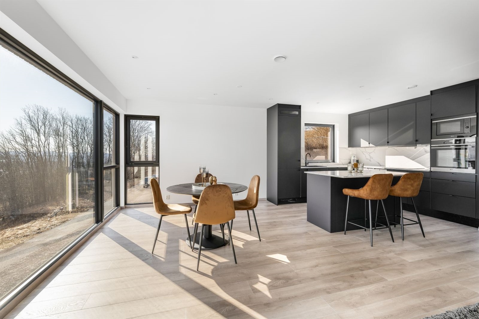 Kjøkkendelen har en pen takhøy innredning fra Systemkjøkken med sorte slette fronter, laminert benkeplate med stålvask og Kitchen Wall plater over kjøkkenbenk. Galleribilde