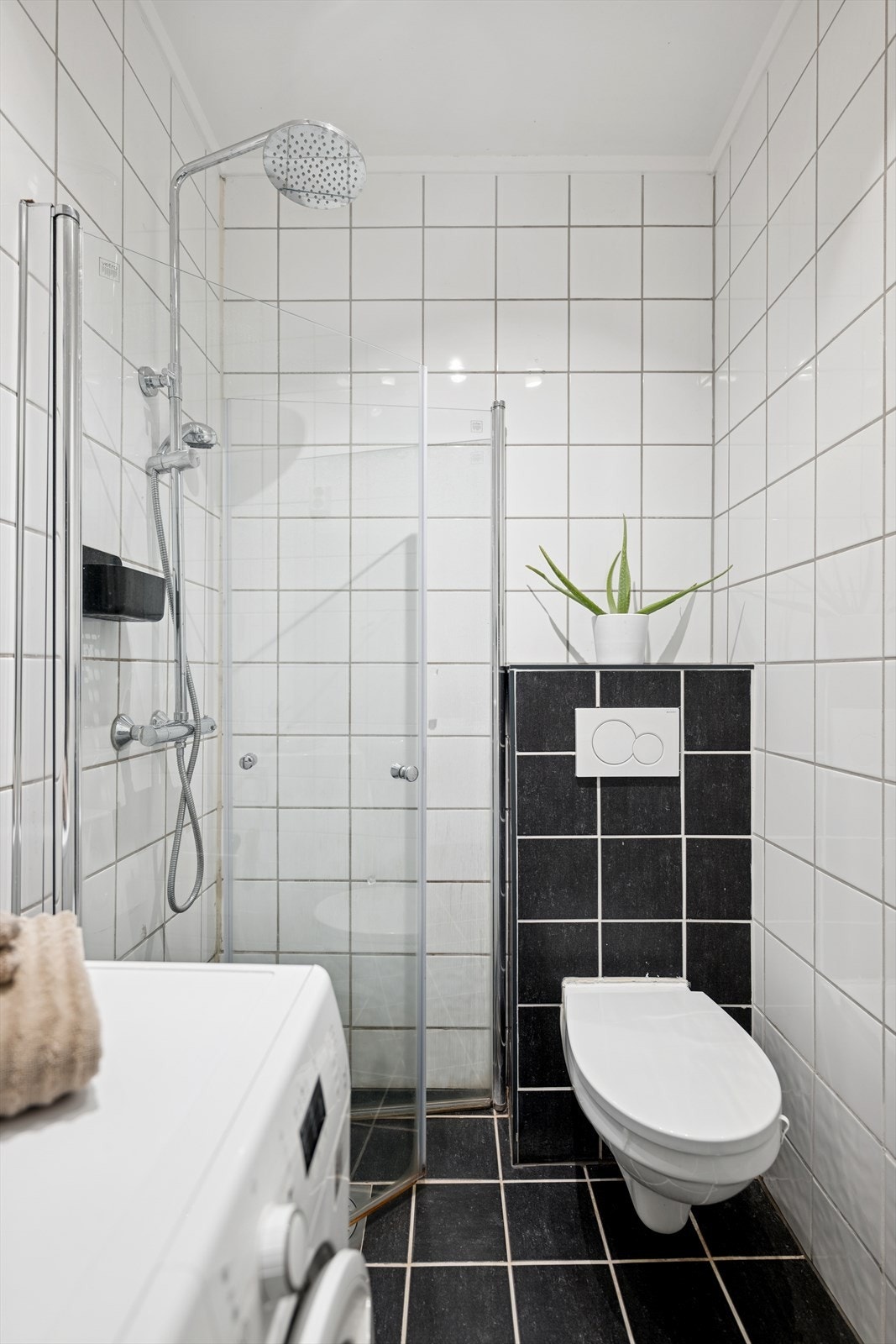 Badet har dusjhjørne, vegghengt wc, opplegg for vaskemaskin og servant med underskap. Galleribilde