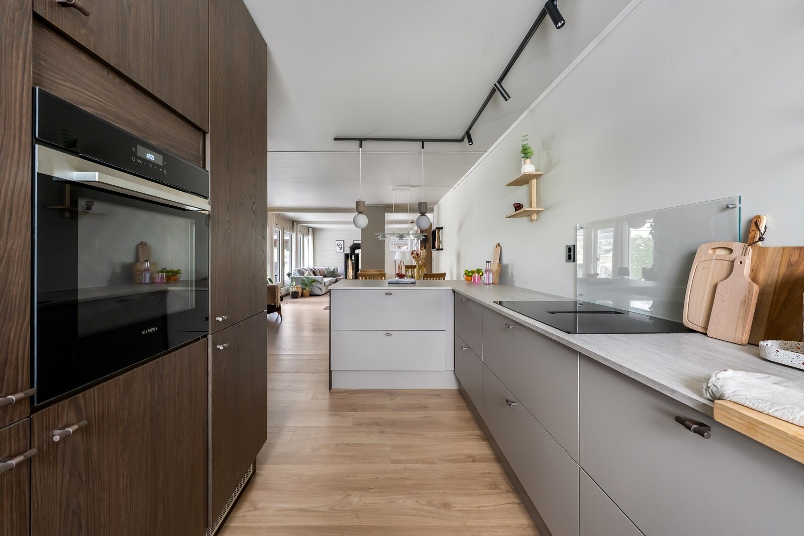 Kjøkkenet har lyse og mørke, glatte fronter og en laminert benkeplate, med hvitevarer inkludert kjøleskap, fryser, oppvaskmaskin, platetopp og ovn. Galleribilde