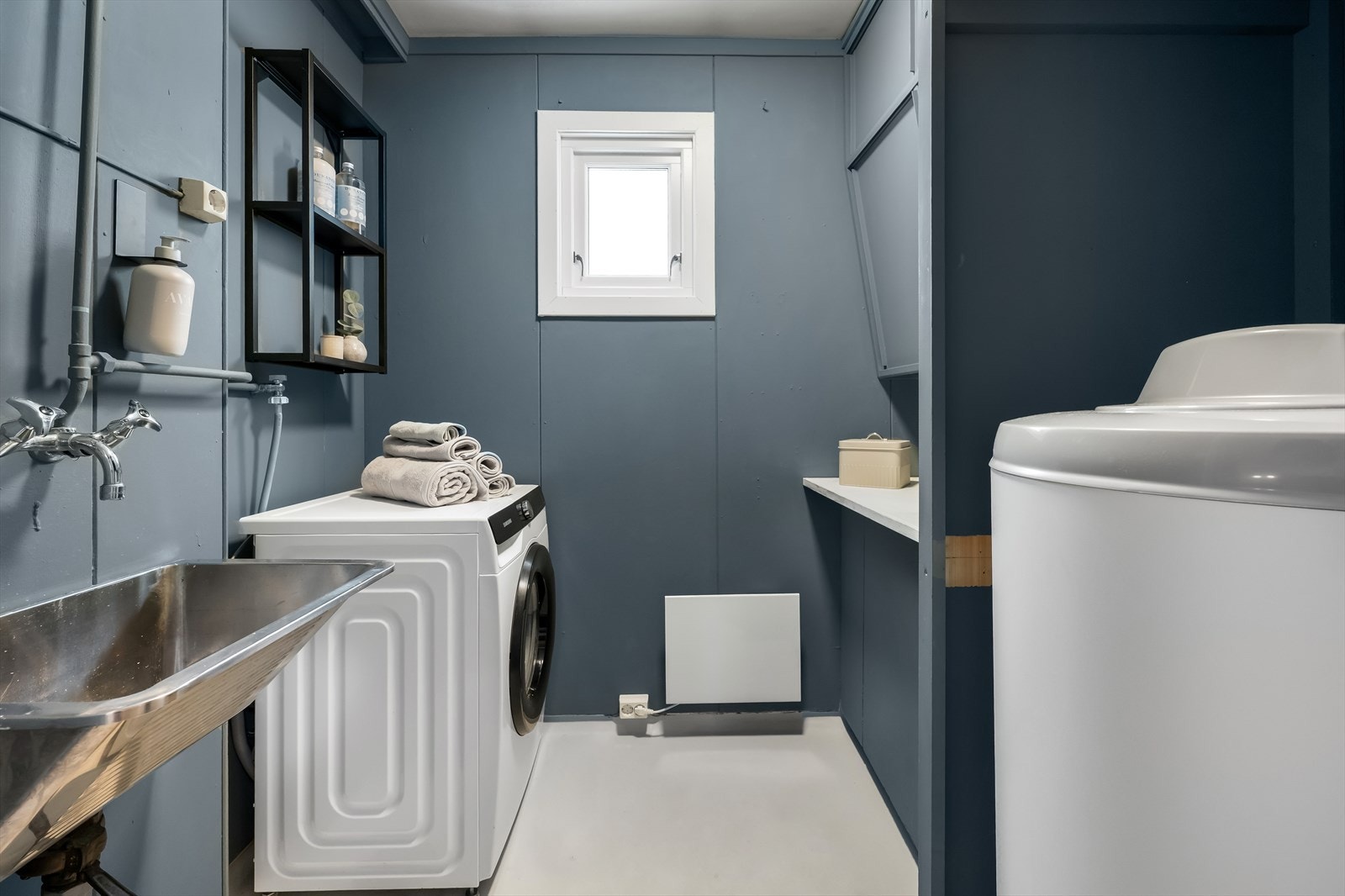 Vaskerommet har en praktisk plassering av vaskemaskin og varmtvannsbereder, med god arbeidsplass ved vasken. Galleribilde