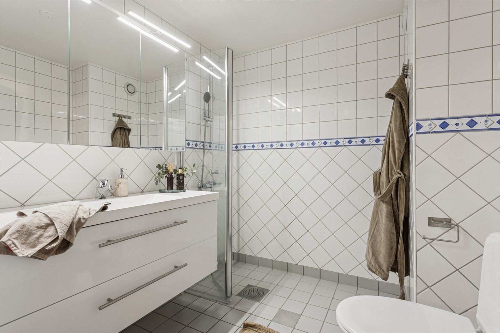 Leiligheten har et tidløst, flislagt baderom med varmekabler i gulv. Galleribilde