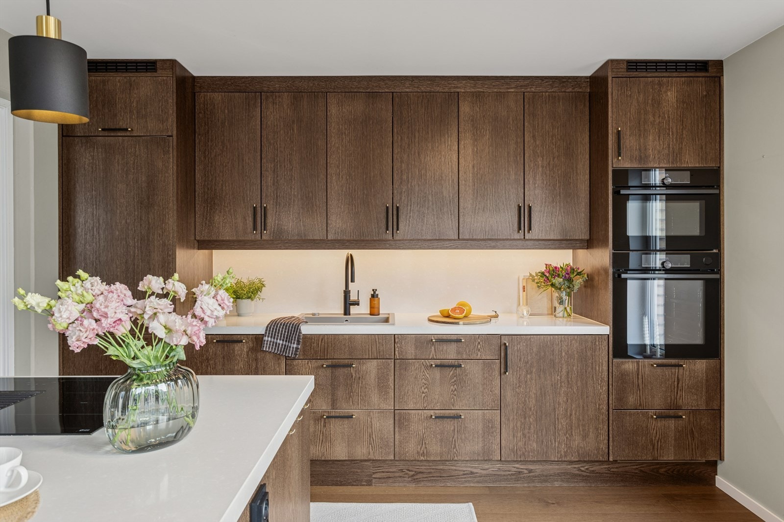 Boligen har et lekkert, plassbygget kjøkken fra Bakken Treverksted med glatte skapfronter og benkeplate i kompositt - backsplash i samme utførelse. Galleribilde