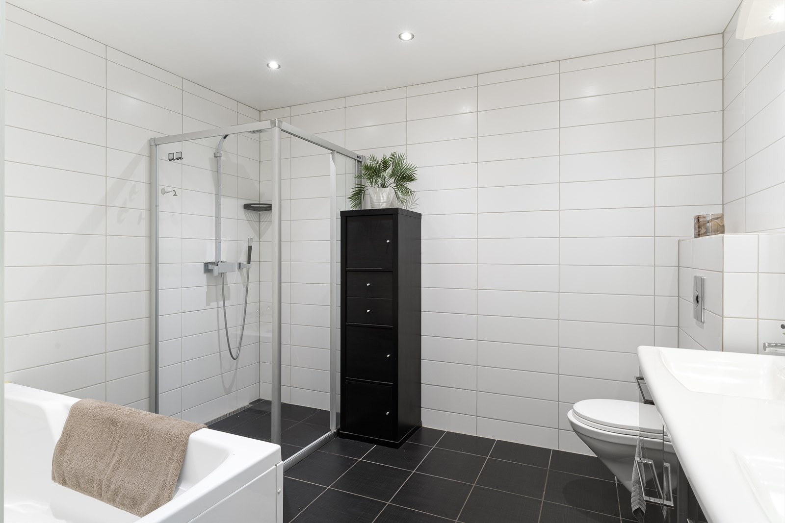 Stort helfliset bad med vegghengt wc, vask i seksjon, speil med belysning, dusj med glassdører og badekar. Varmekabler i gulv. Galleribilde