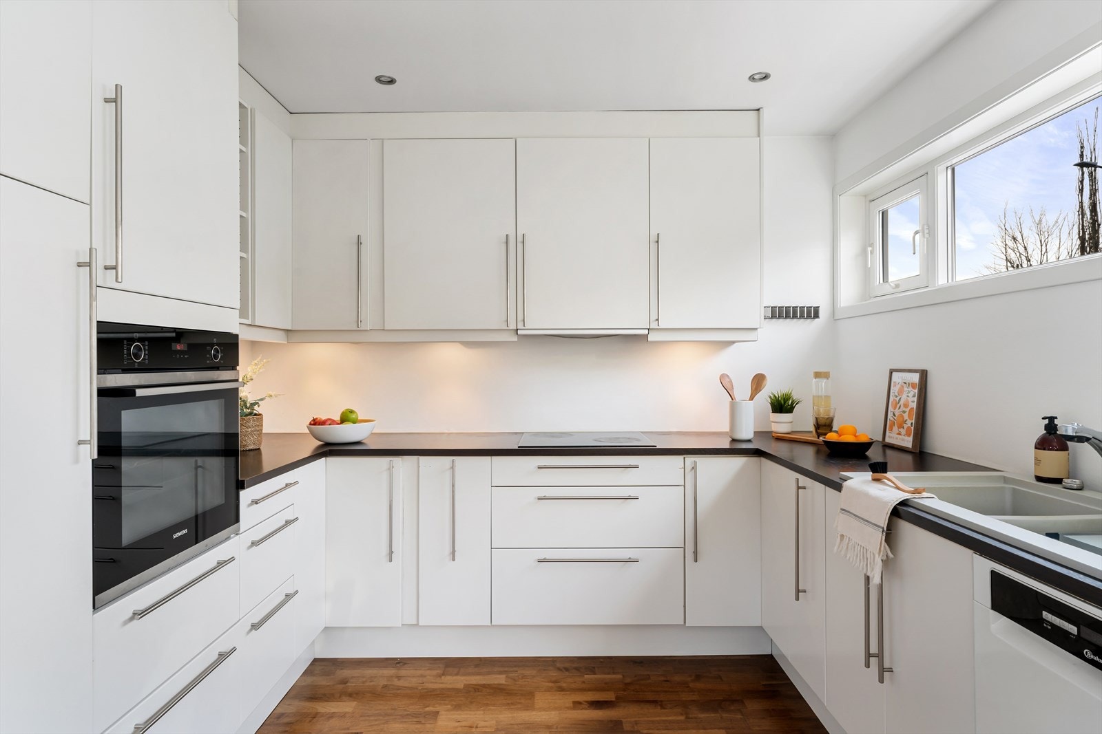 Hvitt kjøkken med god lagringsplass i skuffer og skap. Integrert stekeovn i god arbeidshøyde. Galleribilde