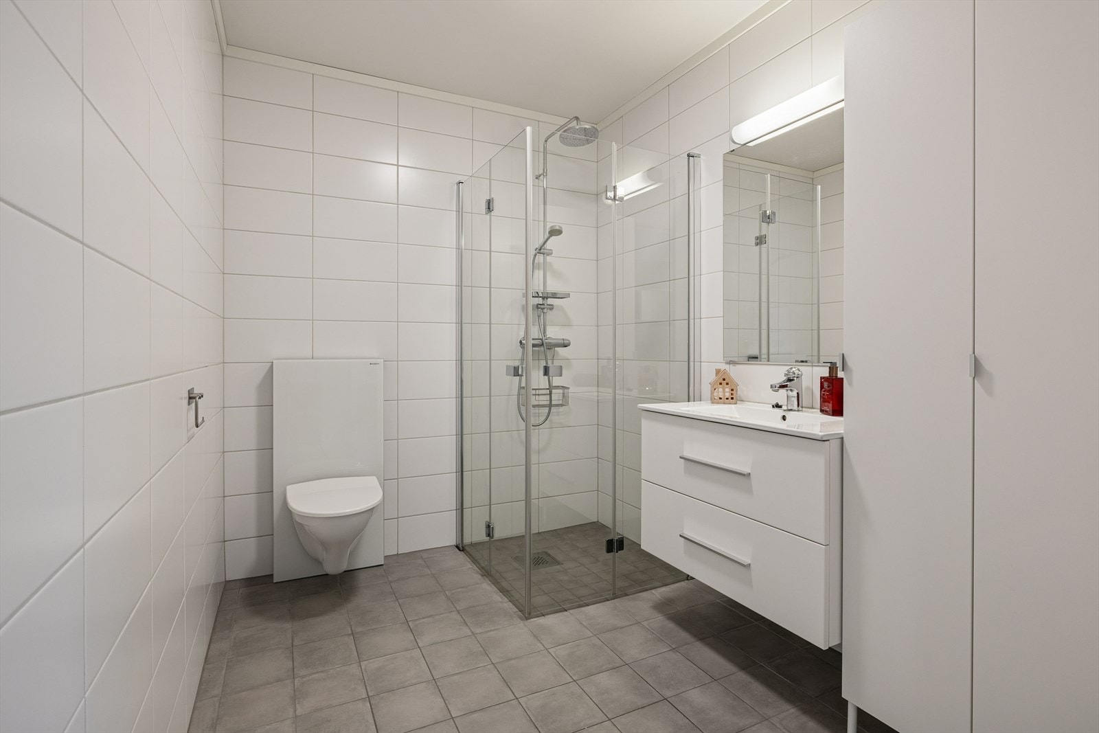 Nøytralt flislagt bad. Det ble lagt nye fliser på gulvet i 2019/2020. Praktiske, innfellbare dusjvegger. Galleribilde