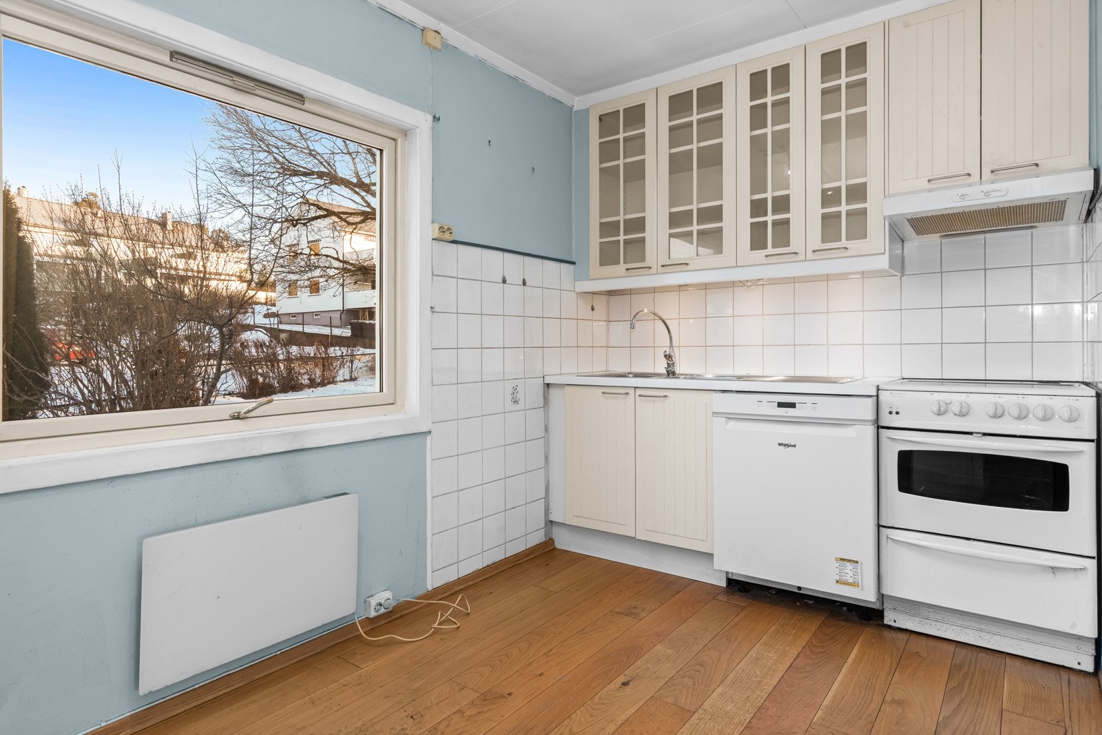 Eldre malt kjøkkeninnredning med benkebeslag og avtrekk over kokesone. Galleribilde