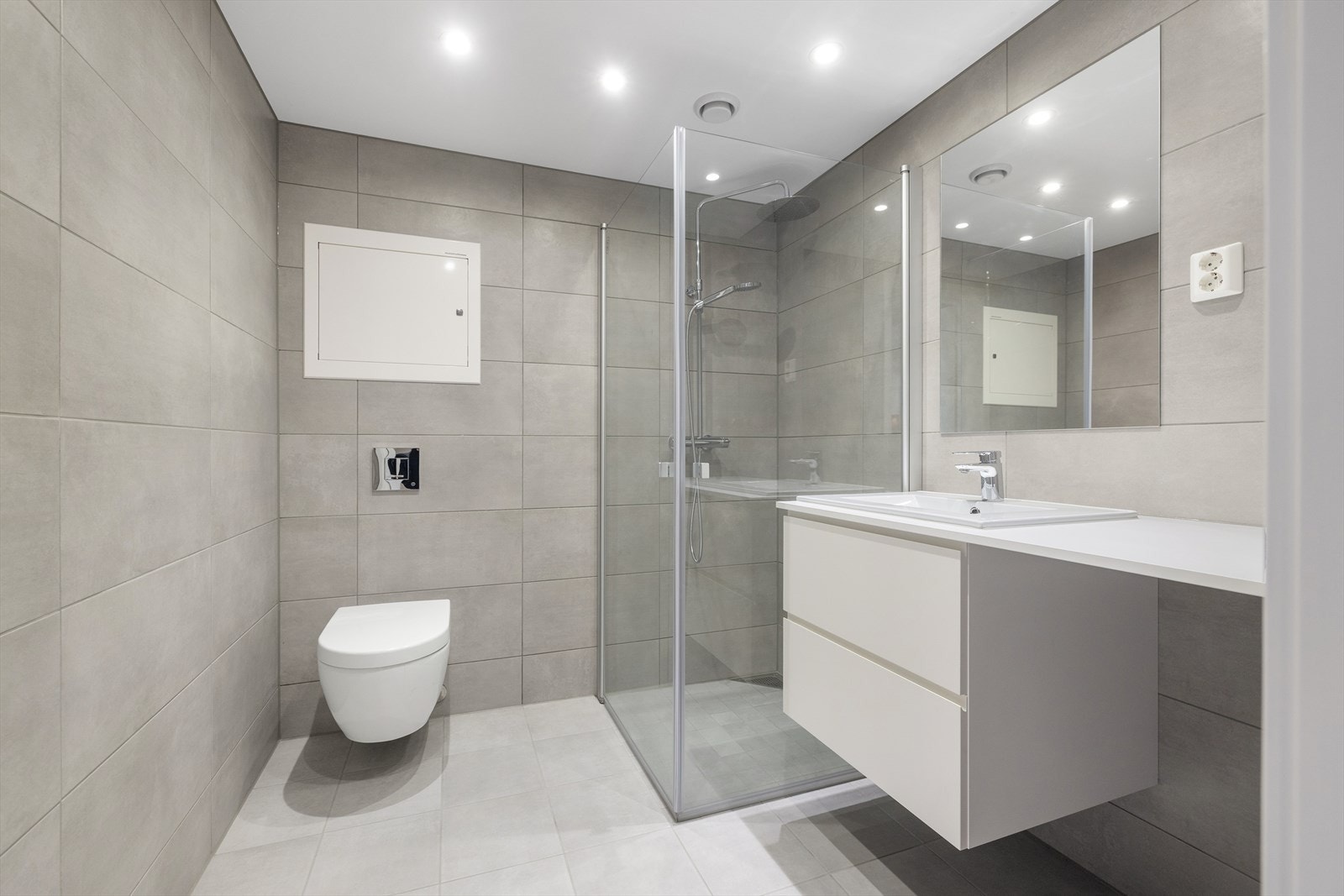 Lekkert og herlig bad med LED-downlights i himling med dimmer og vannbåren gulvvarme. Baderomsinnredning har skuffeseksjon, med skuffer i hvit utførelse og porselensservant med ettgreps servantbatteri tilpasset servantseksjonens bredde. Galleribilde