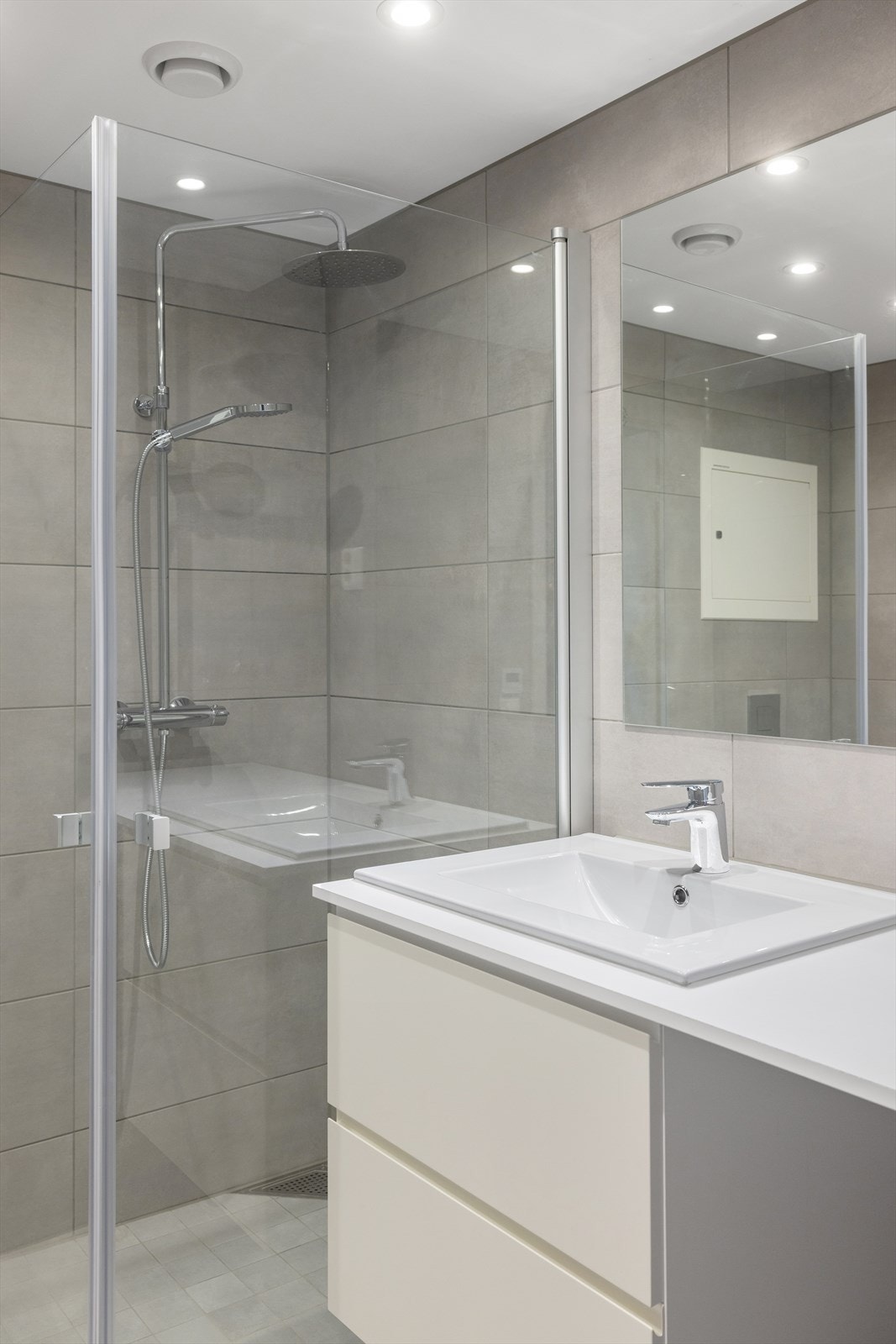 På veggene er det 30 x 60 cm flis, på gulvet 30 x 30 cm, og i dusjsonen er det 10 x 10 cm - alt i samme flisdesign og farge. Det gir et delikat og ryddig uttrykk, og en perfekt base du kan style slik du måtte ønske. Galleribilde