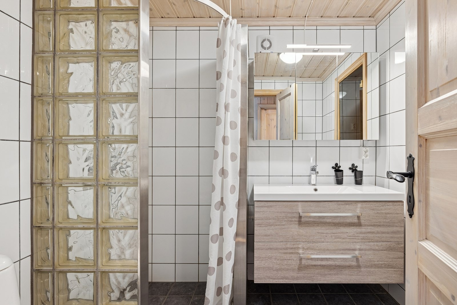 Badegulv med varmekabler, stor og god dusjnisje, heldekkende servant med speilskap og lys - samt opplegg til vaskemaskin og inngang til badstue. Galleribilde