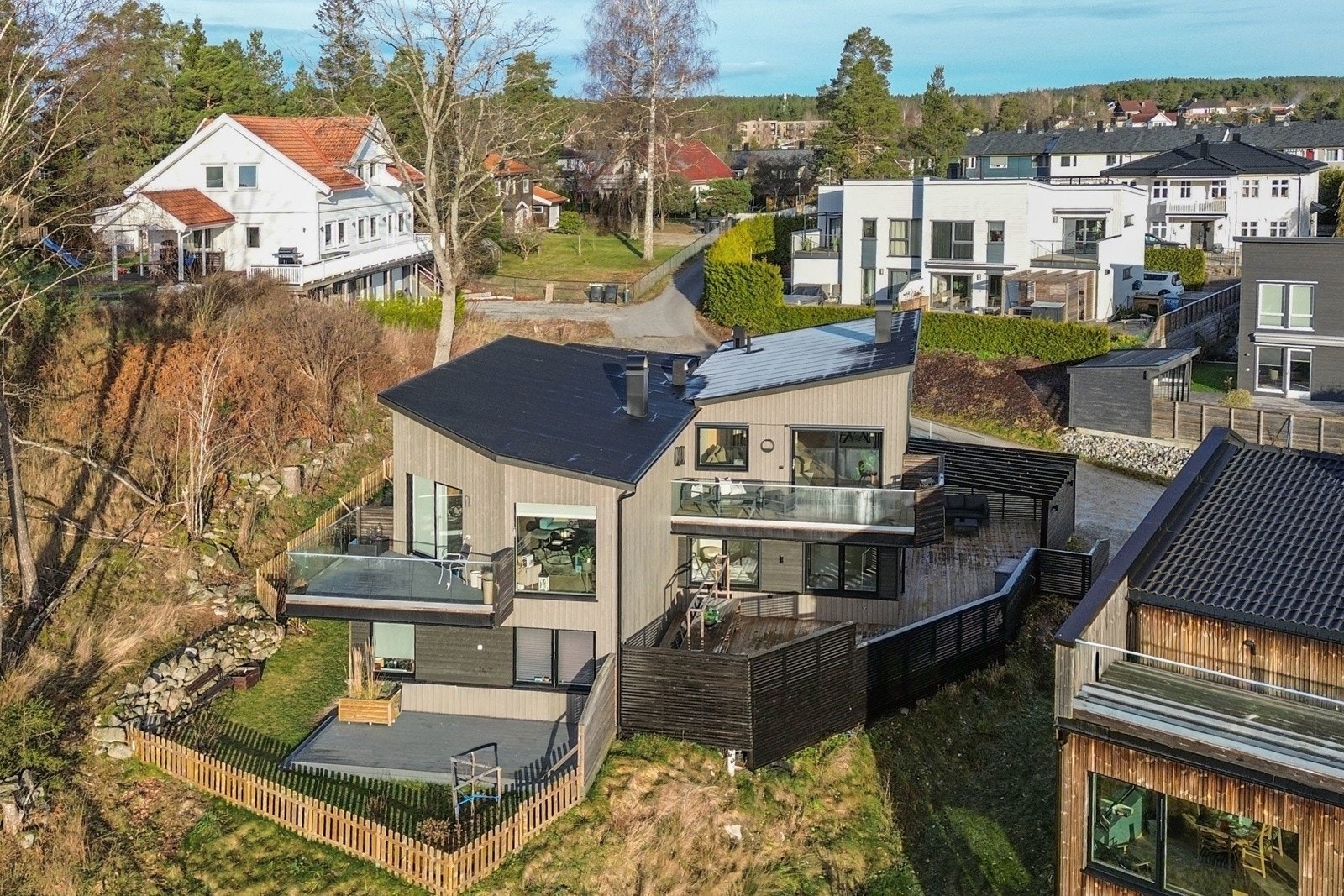 Delvis flat og skrånende tomt, opparbeidet med gårdsplass, plen, grus og platting. Galleribilde