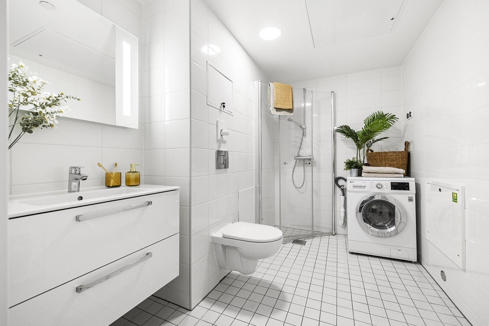 Badet har innredning med heldekkende servant, veggmontert toalett, hjørnedusj og opplegg for vaskemaskin. Galleribilde