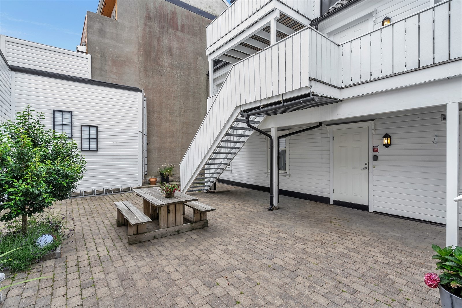 Pent opparbeidet felles bakgård med belegningsstein og solrik felles uteplass Galleribilde