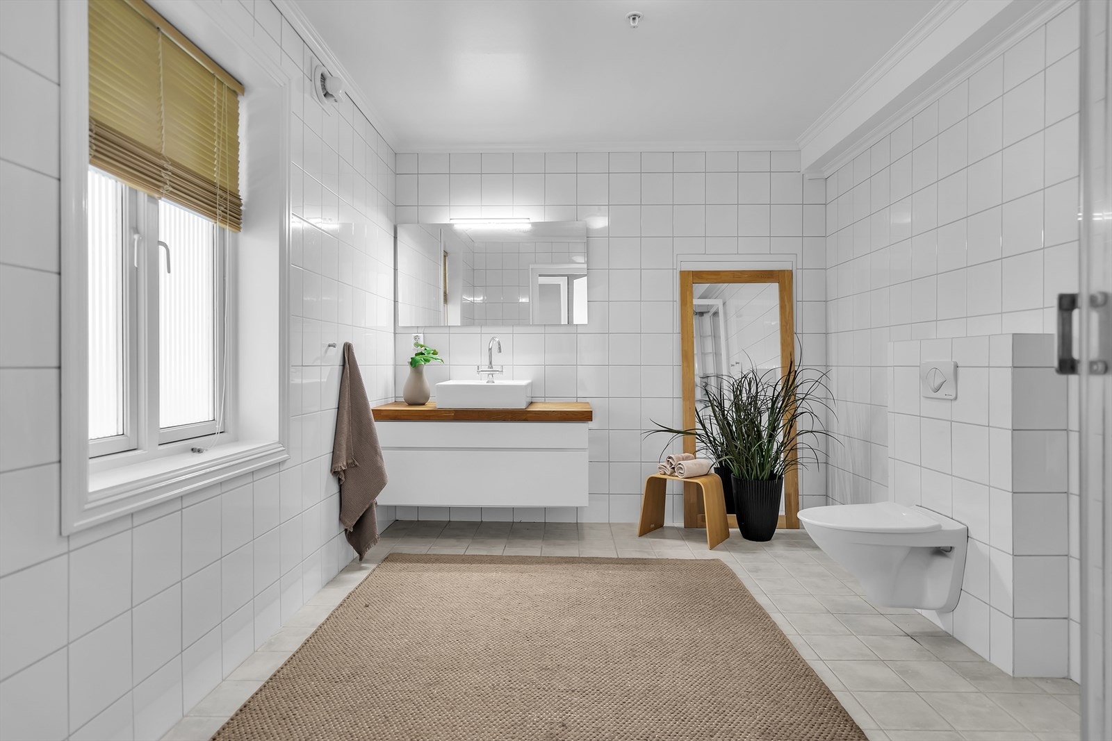 Baderommet er av god størrelse, flislagt med varme i gulv. Vegghengt toalett, dusjkabinett og servant med oppbevaring. Galleribilde