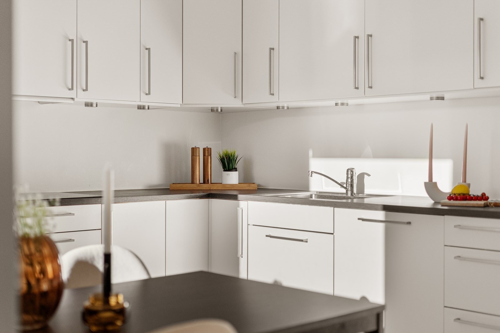 Kjøkkenet har hvite slette fronter og mørktonet benkeplate, samt integrerte hvitevarer som stekeovn, oppvaskmaskin, platetopp og kjøleskap. Galleribilde