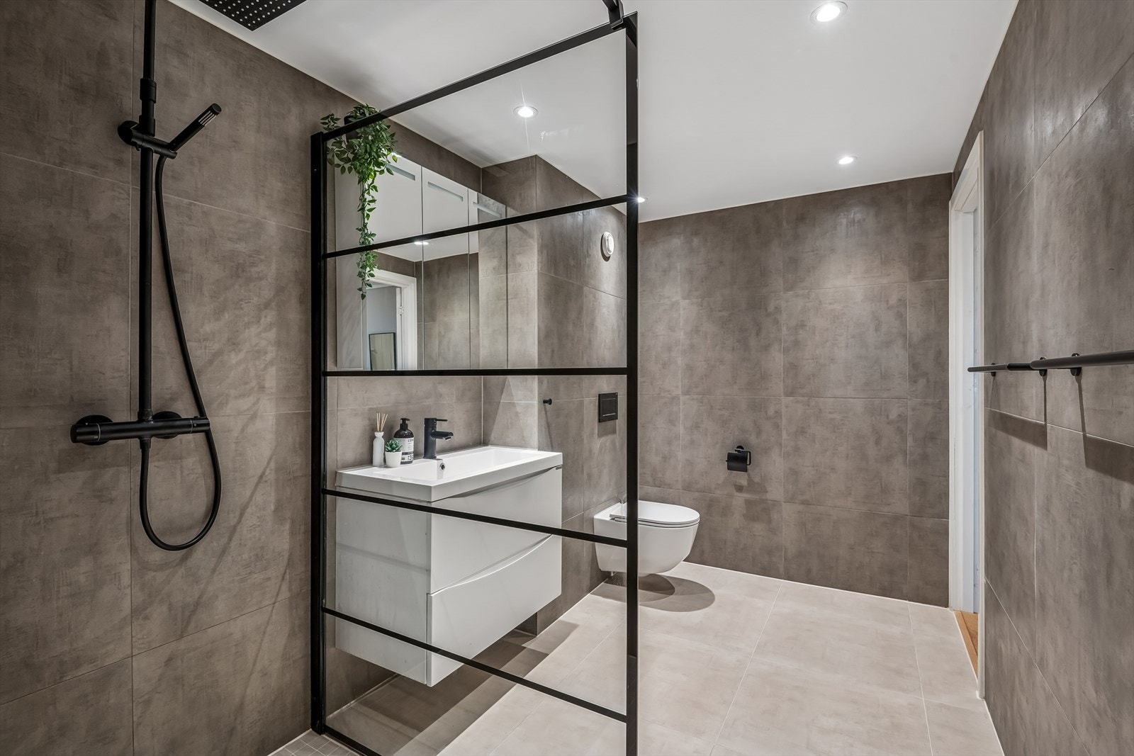 Badet er lekkert og ble pusset opp i 2019. De store flisene kombinert med svarte detaljer gir badet en røff stil. Galleribilde