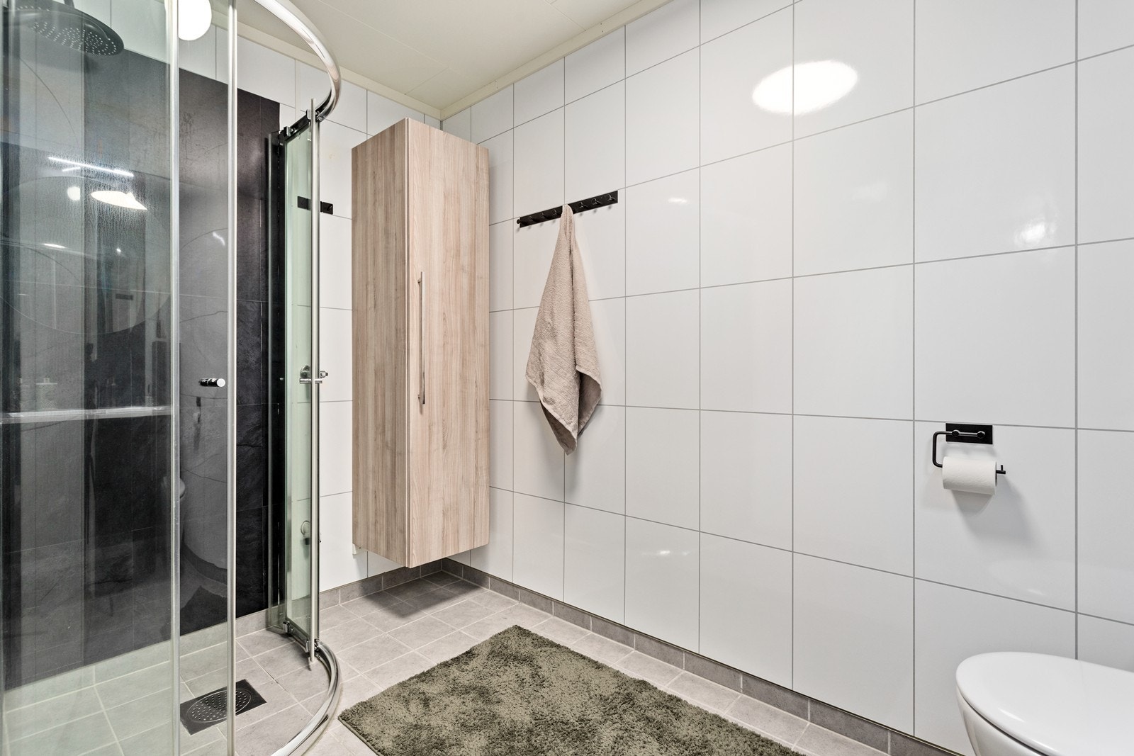 Badet har varmekablar i golv og er utstyrt med baderomsinnreiing, høgskap, dusjhjørne og vegghengt toalett. Galleribilde