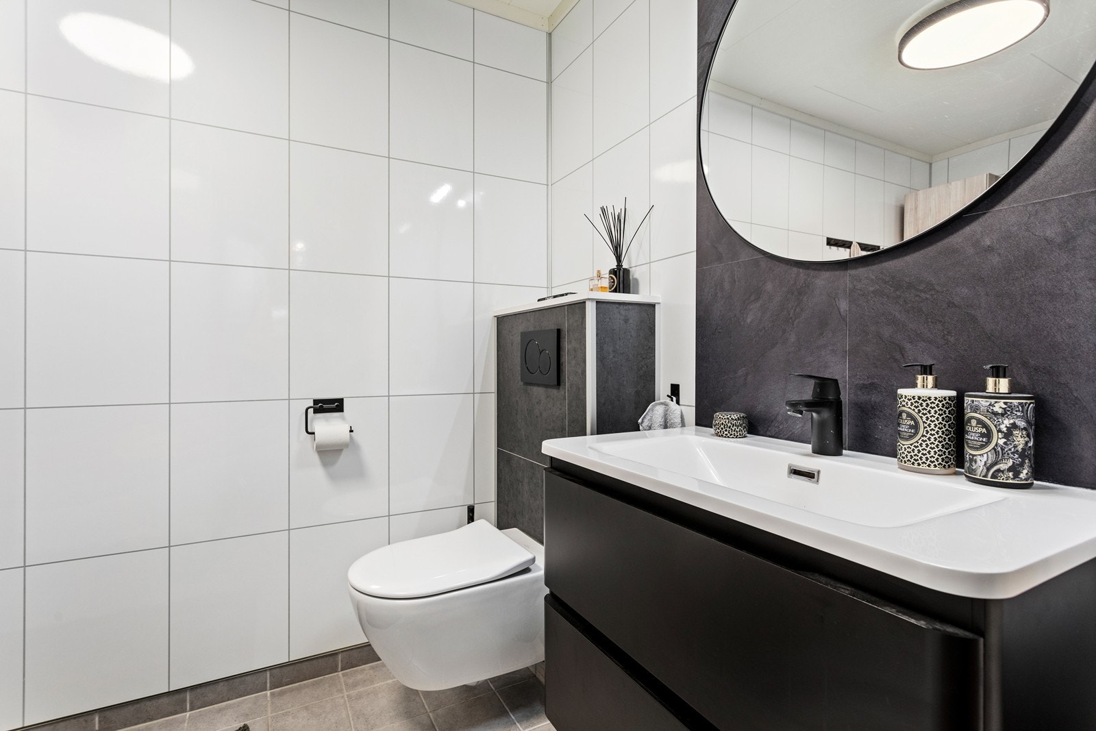 Bad i nøytral utførelse med flislagt golv og baderomsplater på vegger. Galleribilde