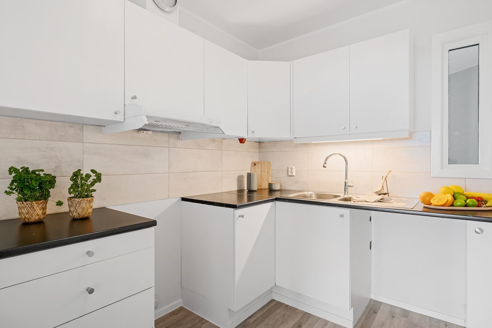 - Lyst kjøkken med sorte benkeplater, flislagt bakvegg og godt med over- og underskap for oppbevaring - Galleribilde