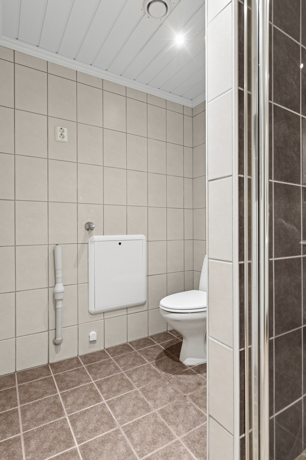 På badet er det dusjhjørne med glassdører, gulvstående toalett og baderomsinnredning med under- og overskap. Opplegg for vaskemaskin. Galleribilde