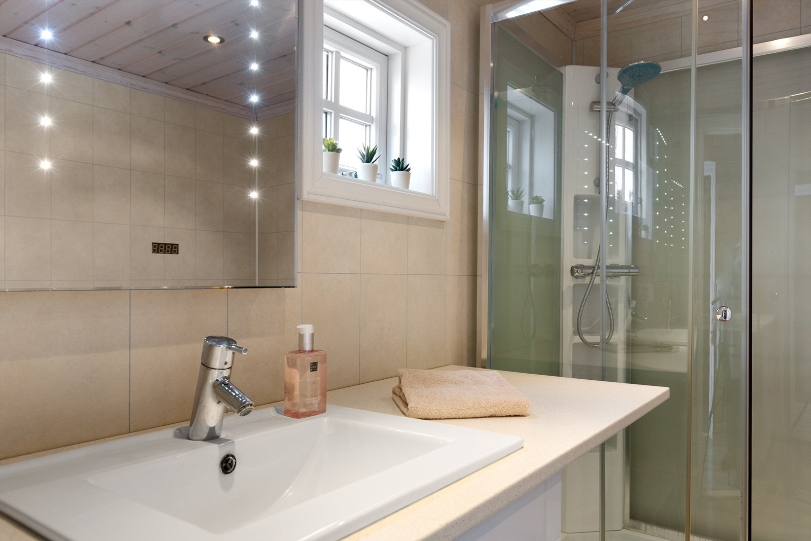 Her er det lys baderomsinnredning med nedfelt servant, speil med belysning, frittstående dusjkabinett, toalett og høyskap med varmtvannsbereder på ca. 50 liter (fra 2013). Det er også elektrisk styrt vifte. Galleribilde