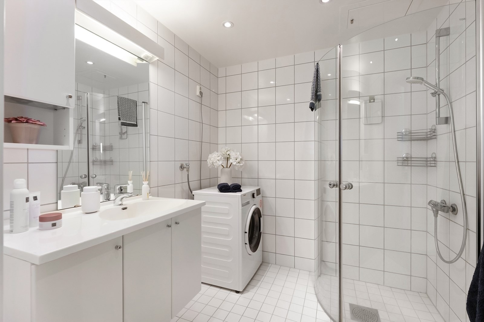 Helstøpt benk med servant, vegghengt toalett og svingbare dusjvegger i glass. Galleribilde