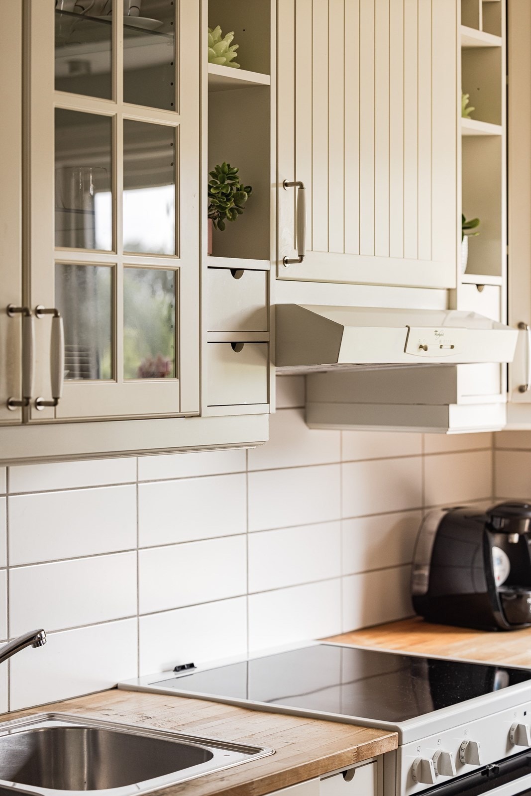 Praktisk med lyse fliser i benkeryggen og kjøkkenventilator med avtrekk. Galleribilde