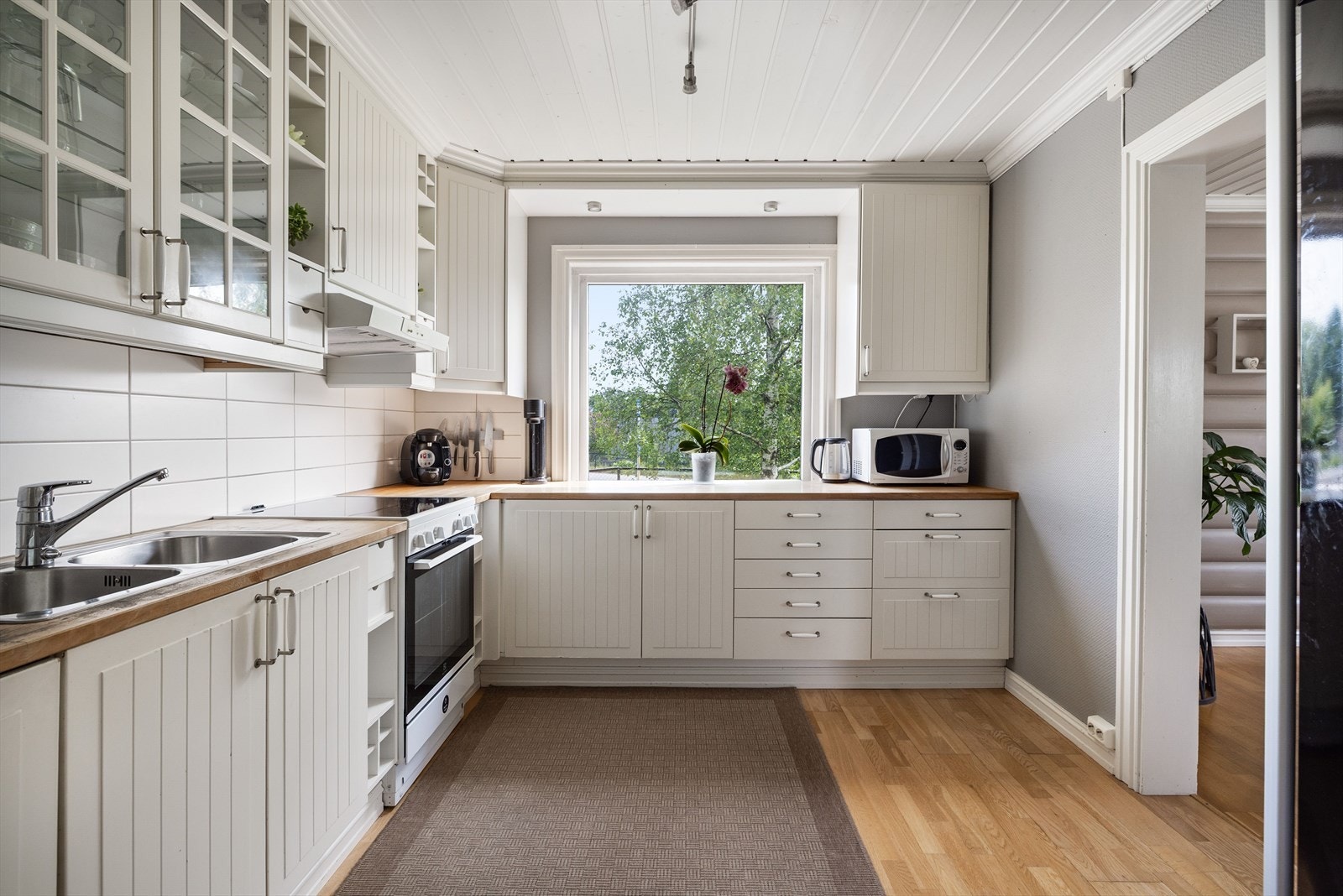 Innredningen har lyse rillede fronter og heltre benkeplate med nedfelt oppvaskkum. Kjøkkenet er utstyrt med integrert oppvaskmaskin som medfølger i handelen. Galleribilde