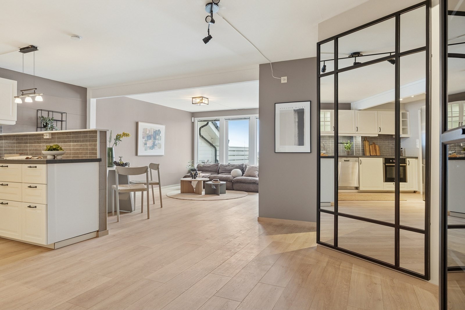 Fra kjøkkenet åpner rommet seg opp mot stuen og terrassen - en gjennomført og sosial planløsning. Her flyter hverdagen sømløst fra matlaging til avslapning. Galleribilde