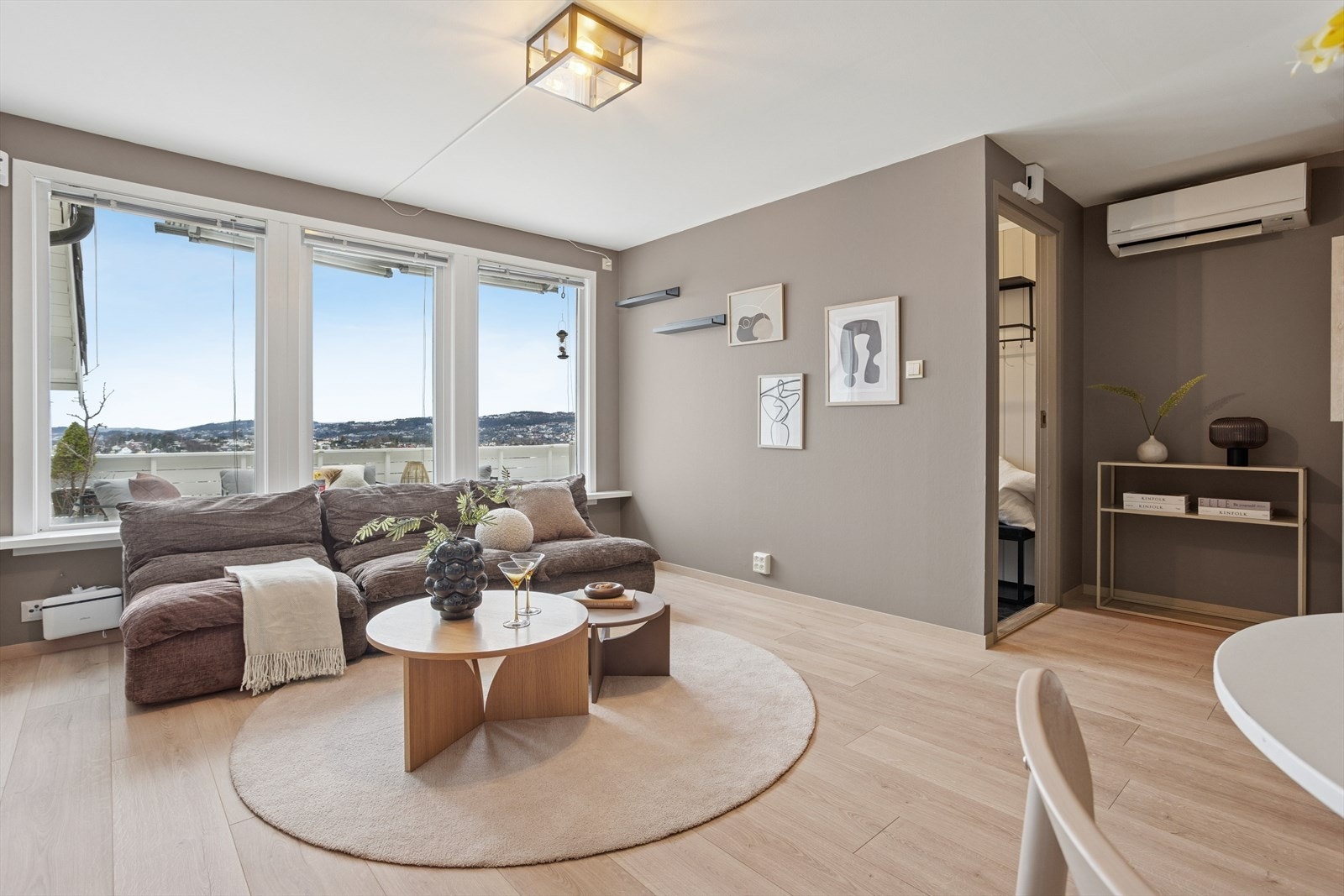 Stuen har mye naturlig lys fra de store vinduene og har utsyn mot terrassen og Fana. Varmepumpen og peisovnen fra 2020 i rommet gir både komfort og lavere energibruk. Galleribilde