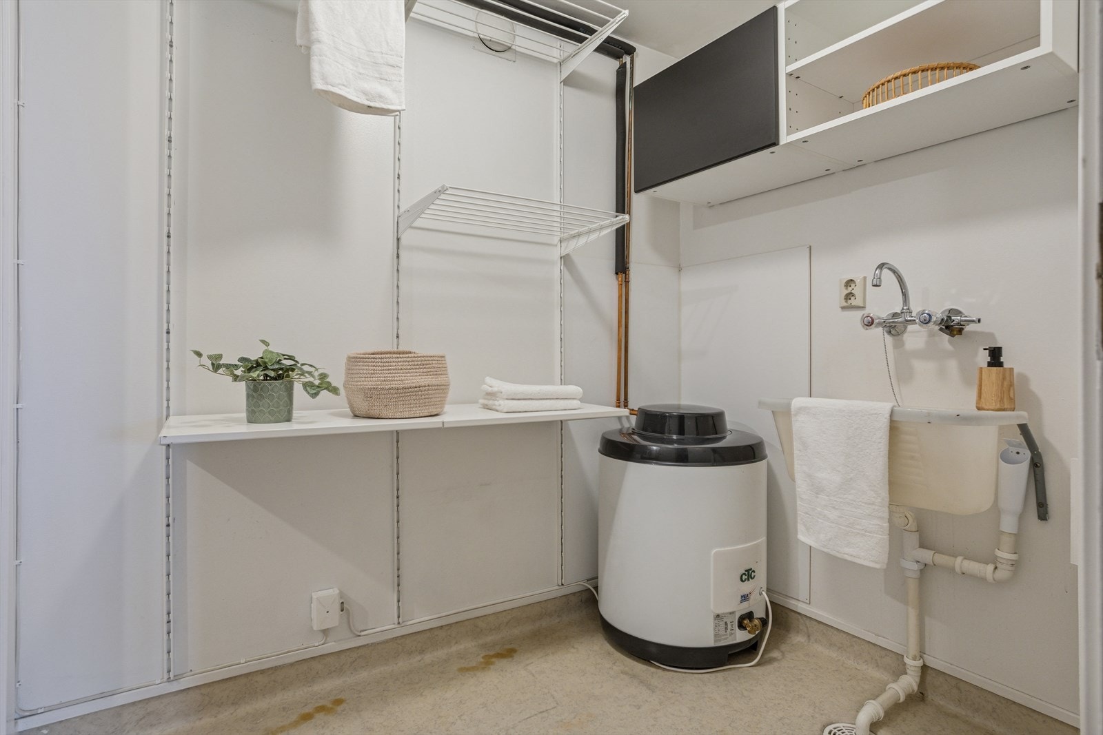 Vaskerommet er funksjonelt innredet med utslagsvask, hyller og opplegg for vaskemaskin og tørketrommel. Varmtvannstanken fra 2022 gir trygg og stabil drift i hverdagen. Galleribilde