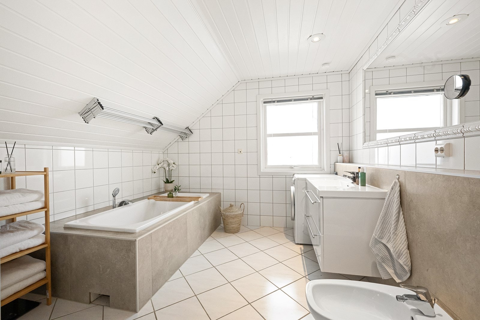 Helfliset bad med nyere innredning og innbygget badekar, dusj og plass til vaskemaskin Galleribilde