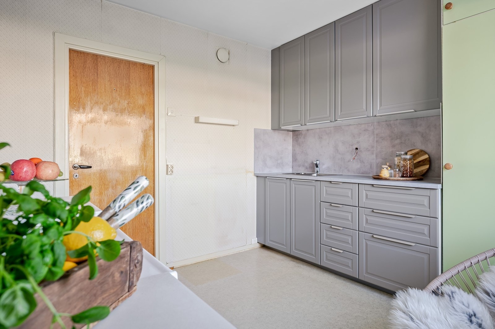 Del med nyere innredning som har grå profilerte fronter, laminert benkeplate med nedfelt oppvaskkum og plater i benkeryggen. Galleribilde