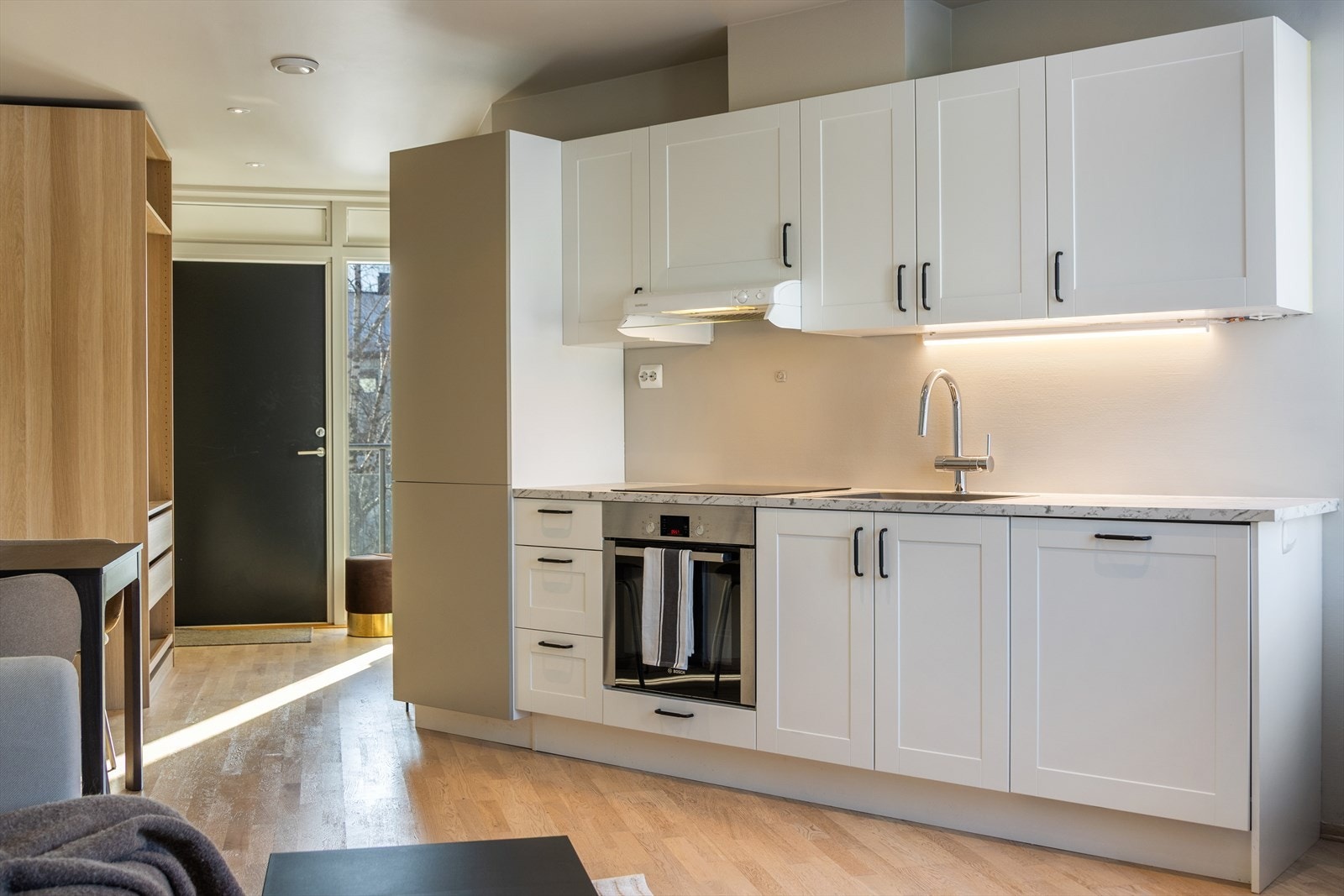 Kjøkkenet har en moderne og plassbesparende innredning samlet langs én vegg Galleribilde