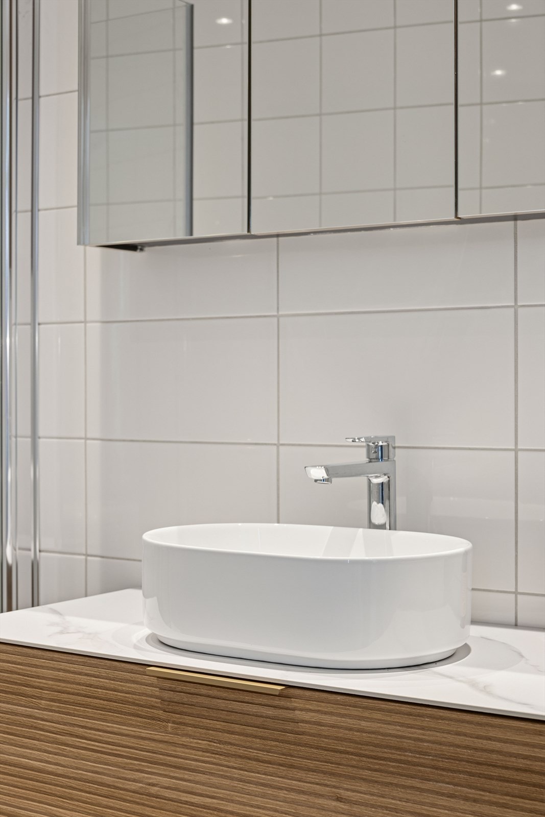 Innredningen består av moderne spilefronter, speilskap over servanten og en praktisk skuffeseksjon som gir rikelig med oppbevaringsplass Galleribilde