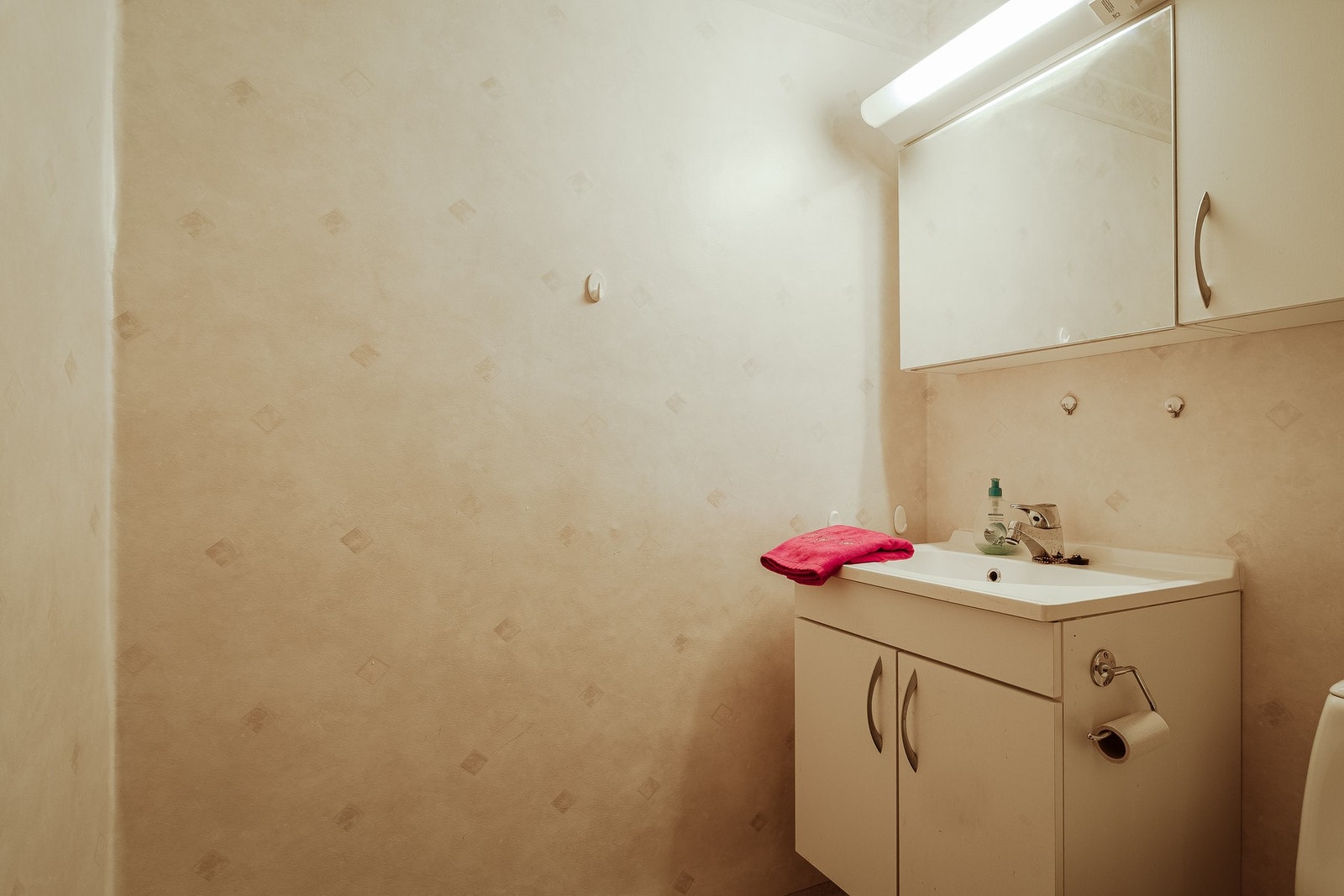 Badet er innredet med gulvskinne med dusjdører, toalett, og servant med underskap. Galleribilde