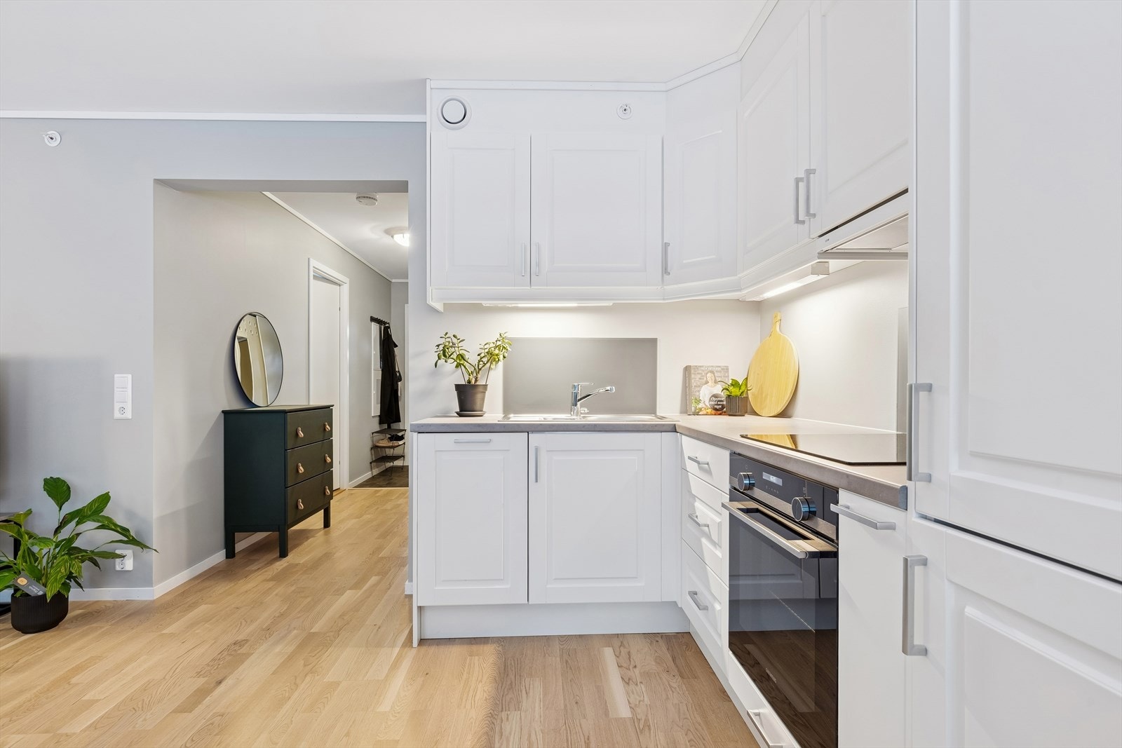 Kjøkkeninnredningen har hvite profilerte fronter og en slitesterk laminatbenkeplate. Galleribilde