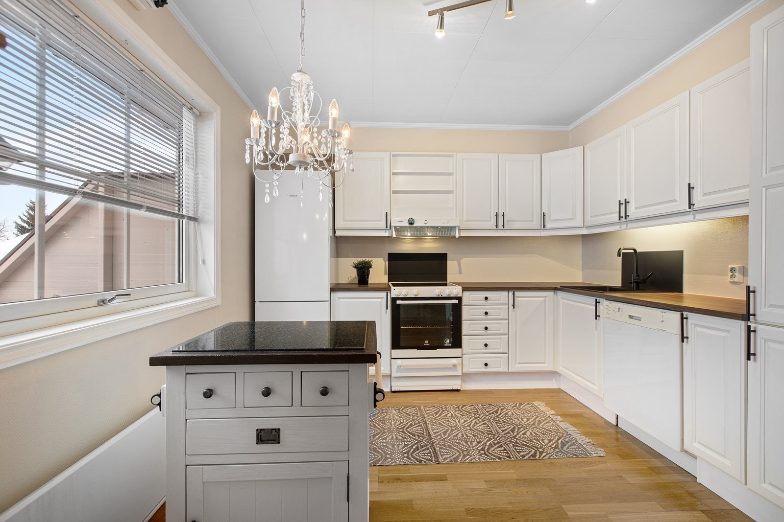 Kjøkkenet er innredet med hvitmalte, profilerte fronter, laminert benkeplate, praktisk belysning under overskap, ett- greps blandebatteri og nedfelt kum. Galleribilde