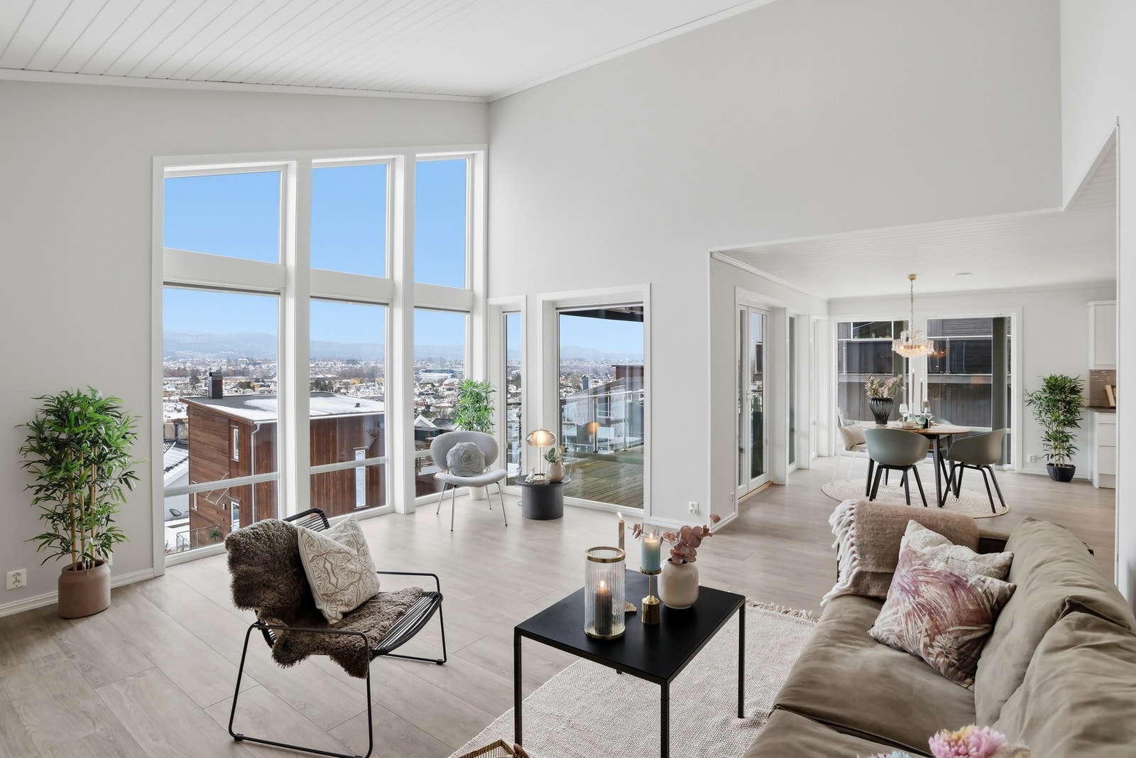 Romslig og elegant stue med stor takhøyde, som ligger i åpen løsning til kjøkkenet Galleribilde