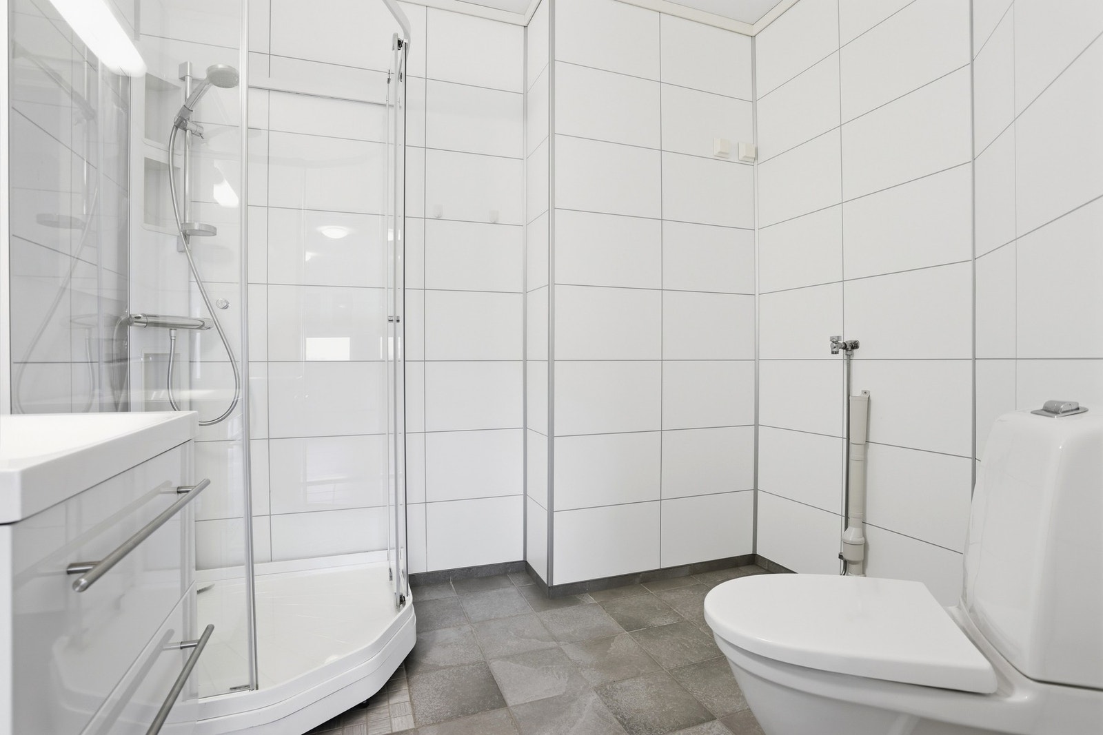 Lyst og delikat bad med flislagt gulv og våtromsplater på vegg Galleribilde