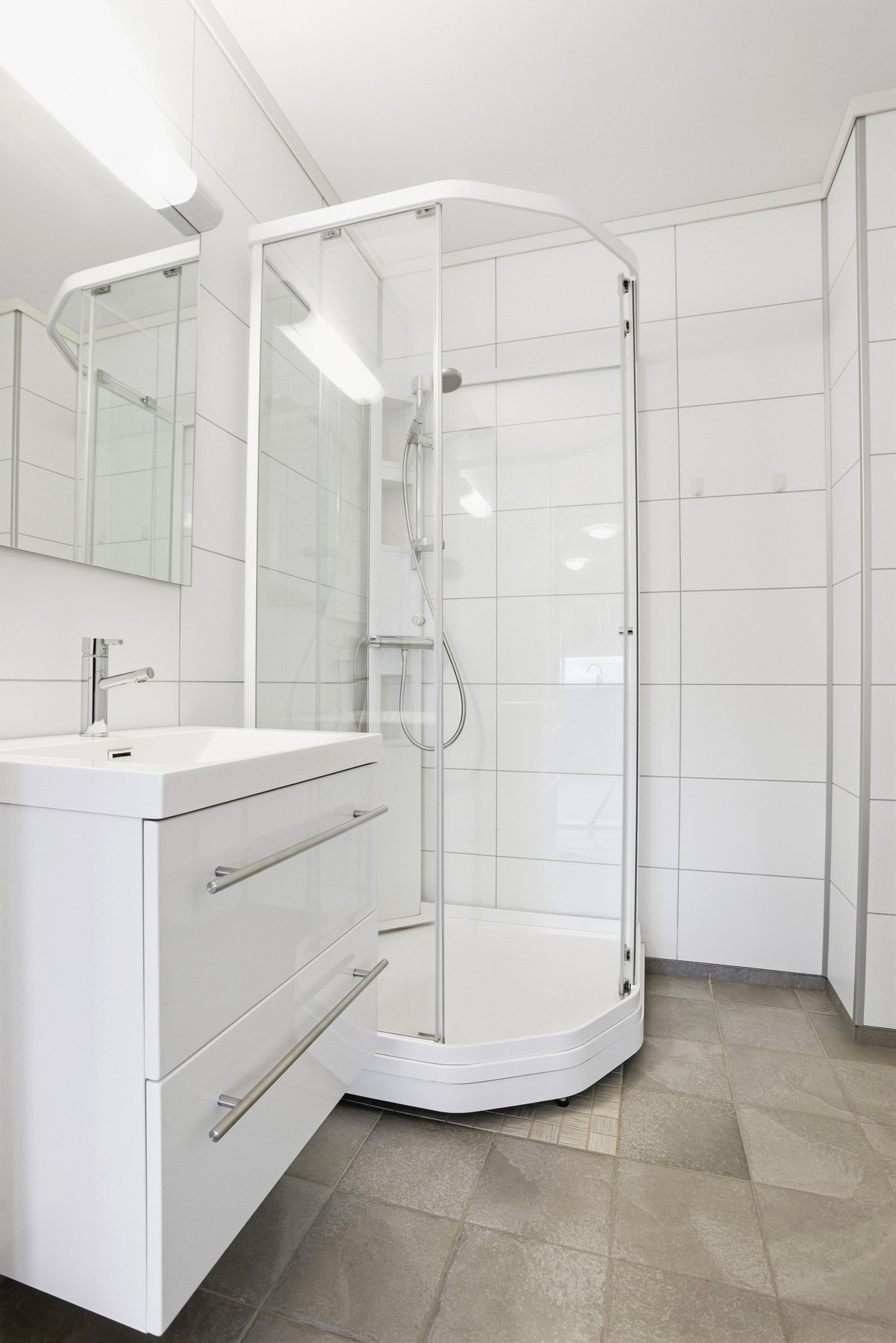 Badet er utstyrt med servant på innredning, gulvstående toalett, montert dusjkabinett og opplegg for vaskemaskin og tørketrommel. Galleribilde